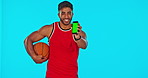 Basketball, phone and chroma key with a man on a blue background in studio for sports marketing. Portrait, exercise and training with a male athlete showing green screen on a mobile screen or display
