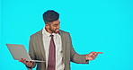 Laptop, business man and pointing in studio isolated on a blue background mockup. Computer, happiness and Indian professional or person typing with advertising, product placement or marketing space.