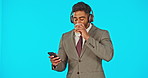 Music headphones, coffee and man with phone in studio isolated on a blue background mockup. Cellphone, tea and happy business person listening, streaming and dancing to audio, radio sound or podcast.