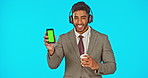 Phone, headphones and business man with green screen in studio isolated on blue background mockup. Face portrait, coffee and happy Indian person streaming music with marketing or product placement.