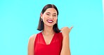 Woman face, pointing and studio with beauty, happiness and smile showing mockup for advertisement. Portrait, isolated and blue background with a happy young female point to show mock up announcement