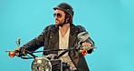 Motorcycle, studio and man with a smile on a ride adventure with wind in hair and confidence. Cool model, isolated and blue background of a person thinking on motorbike and sunglasses on a road trip 