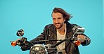 Motorbike, driver and happy man in studio on blue background for road trip, adventure and leather aesthetic. Driving, motorcycle and man riding on mockup, edgy and confident, vintage and retro