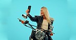 Selfie, blue background and woman on motorcycle with phone for adventure, road trip and holiday mockup. Motorbike, transport and happy girl take picture for social media, post or memory in studio