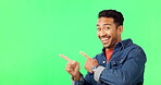 Asian man, pointing and dancing on green screen for advertising or marketing against a studio background. Portrait of happy male showing advertisement, gesture or point to product placement on mockup
