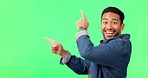 Asian man, pointing and dancing on green screen in product placement or advertisement against studio background. Portrait of happy male showing gesture or point for advertising or marketing on mockup