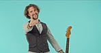 Rock, performance and face of a man with a guitar isolated on a blue background in a studio. Happy, music and portrait of a musician greeting, blowing a kiss and playing an instrument on a backdrop