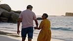 Back of couple, beach and holding hands for walking at sunset on vacation, holiday and relax in retirement. Happy man, woman and senior people in love at ocean for quality time, happiness and partner