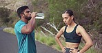 Fitness, man and woman on break drinking water on outdoor path, running exercise or marathon training. Fatigue, runner and personal trainer relax, rest and drink on morning workout on road in nature.