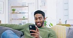 Phone, relax and happy man on sofa in living room for social media, networking and mobile app chat at home. Young Indian person with communication, reading online and internet post on couch or lounge