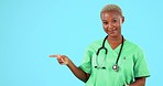 Black woman, doctor and pointing on mockup for advertising or marketing against a blue studio background. Portrait of confident African female medical professional and point gesture for advertisement