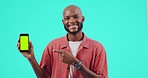 Green screen, phone and man face with advertising mockup, tracking markers and pointing isolated on blue background. Happy african person and presentation of mobile app or online web space in studio