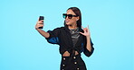 Selfie, sunglasses and woman with rock sign in studio isolated on blue background mockup. Photograph, hand gesture and stylish female person with profile picture, social media fashion and happy emoji