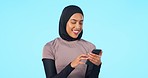 Cellphone, smile and muslim woman in a studio networking on social media, mobile app or internet. Happy, communication and islamic female model browsing online with phone isolated by blue background.