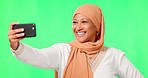 Islamic woman, selfie and smile by green screen, studio background and happy for social media mock up. Female muslim model, happy influencer and photography for blog, app or profile picture in mockup