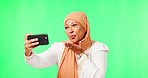 Islamic woman, selfie and green screen with kiss, studio background or happy in social media mock up. Female muslim model, influencer and photography with sign, emoji and profile picture in mockup