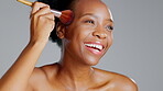 Beauty, makeup and brush with black woman in studio for foundation, blush and self care. Glow, facial and cosmetics with girl model and tool for confidence, powder and natural on grey background