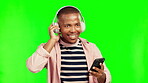 Music headphones, phone and black man on green screen in studio isolated on a background. Radio, listening and happy African person dance to audio playlist, jazz podcast or streaming hip hop sound.