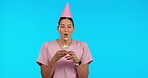 Birthday, party and wish with a nurse woman in studio isolated on a blue background for celebration. Smile, healthcare and a happy young female medicine professional blowing out a candle on a cupcake