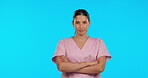 Face, nurse and serious woman with arms crossed in studio isolated on blue background. Portrait, confident surgeon or medical professional, doctor or person in Brazil for healthcare, mockup and space