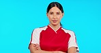 Ready, sport and face of a woman with arms crossed isolated on a blue background in a studio. Expert, fitness and portrait of a young girl for soccer, football training and sports motivation