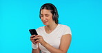 Phone, music and dance with a woman on a blue background in studio streaming an audio playlist. Mobile, radio and headphones with a happy young female listening to sound using an internet app