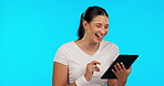 Tablet, research and funny with a woman on a blue background in studio for social media browsing. Comic, technology and app with a happy young female laughing at a meme while surfing the internet