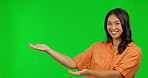Happy asian woman, hands and presentation on green screen for advertising against a studio background. Portrait of female person showing palm for advertisement, news or marketing with mockup space