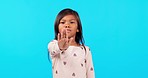 Girl child, hand and stop in studio, face and sign for vote, voice or power to say no by blue background. Young female kid, open palm and portrait in protest, warning or opinion with emoji for choice