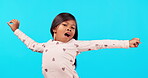 Tired, yawning and stretching with a girl in pajamas on a blue background isolated in studio at bedtime. Portrait, kids and yawn with a young female child indoor to wake up after sleep at night