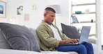 Man, laptop and typing on couch for work from home, project management or concentration for freelance job. Young digital entrepreneur, computer and sofa with report, research or focus for copywriting