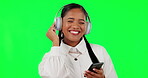 Happy woman, headset and phone listening to music on green screen against a studio background. Calm female person with smile, headphones and mobile smartphone app for audio streaming or sound track