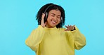 African woman, headphones and dancing in studio with music, audio streaming and happy by blue background. Gen z girl, student or model with sound tech, radio or dance with smile, listen and freedom