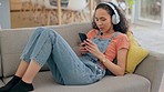 Music, woman with smartphone and headphones listen on sofa in living room of her home for relaxation. Technology or connectivity, streaming and female person listening to radio or podcast on a couch