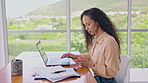 Laptop, phone and a business woman at her desk in the office doing research on a report for work. Computer, communication and notebook with a young female employee working in a glass workplace