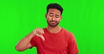 Green screen, thumbs down and face of onfused Asian man with doubt, decision and choice in studio. Unsure, hand sign and portrait of male person on chromakey background with vote, review and feedback