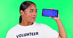 Woman, volunteering and phone on green screen for charity, community service or charity information on mobile app. Face, funny and NGO person with video space, tracking markers and studio background