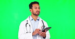 Man, doctor and thinking with tablet, green screen in studio background for cardiology with indian. Service, male surgeon and technology with typing at clinic for healthcare, online or communication.
