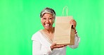 Face, green screen and senior woman with a package, celebration and excited with a brown bag against a studio background. Portrait, female person and mature model with a parcel, gift and happiness