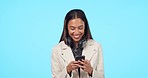 Happy woman, phone and texting in studio, laughing and reading funny email or message on blue background. Smartphone, joke and female laugh at silly comment, post or online comic or streaming meme