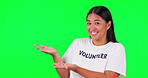 Green screen, volunteer and hands of a woman with presentation space for charity information. Face of happy asian person with hand gesture and tshirt for nonprofit, NGO help or advertising in studio