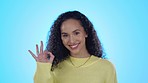 Okay sign, happy and face of woman in studio for approve, agreement or perfect on blue background. Yes emoji, winner and portrait of female person with hand gesture for success, support or thank you