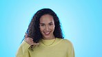 Flirting, happy and woman with a call me gesture in a studio with a wink and positive mindset. Happiness, smile and portrait of a young female model with a phone hand sign isolated by blue background