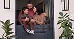 Love, speaking and couple with their child by the door of their family house for fresh air. Happy, smile and young parents talking, holding and bonding with boy kid by their modern home together.