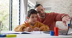 Father, boy child and homework with laptop, writing and helping hand for education, childhood development or care. Man, dad and male kid with home school, notebook and computer with teaching at desk