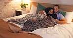 Couple, happy and relax in bedroom with tablet at night, streaming movie and hug. Smile, technology and man and woman in bed on social media app, watching online video and bonding together in home.