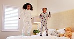 Girl kids, jump and happy on bed with playing, game and excited in family house in morning. Young female children, playful and bedroom for sleepover, friends or sisters for freedom, smile and home