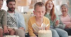 Boy blowing, birthday party or big family with cake in celebration or house party with support or candles. Grandmother, grandfather or excited child eating baked desert with dad, mom or grandparents 