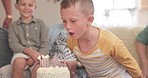 Boy blowing, birthday party or happy family with cake in celebration at home with support, candles or love. Parents, together or excited young child eating baked desert with brother or fun sibling 