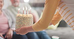 Celebration, family and person with a cake for a birthday, party or surprise in a house. Carrying, candles and hands of a child giving sweet food or dessert on a table for people to celebrate